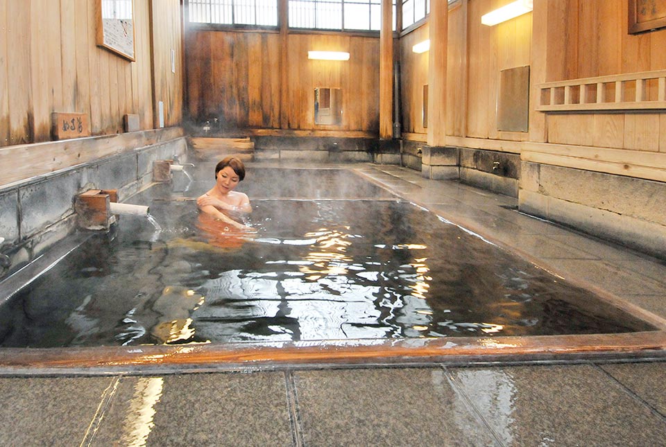 女性が野沢温泉に入っている様子