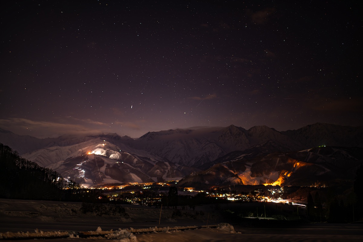 星空の下、ナイター照明が灯るHakuba Valleyのスキー場と麓の町並み