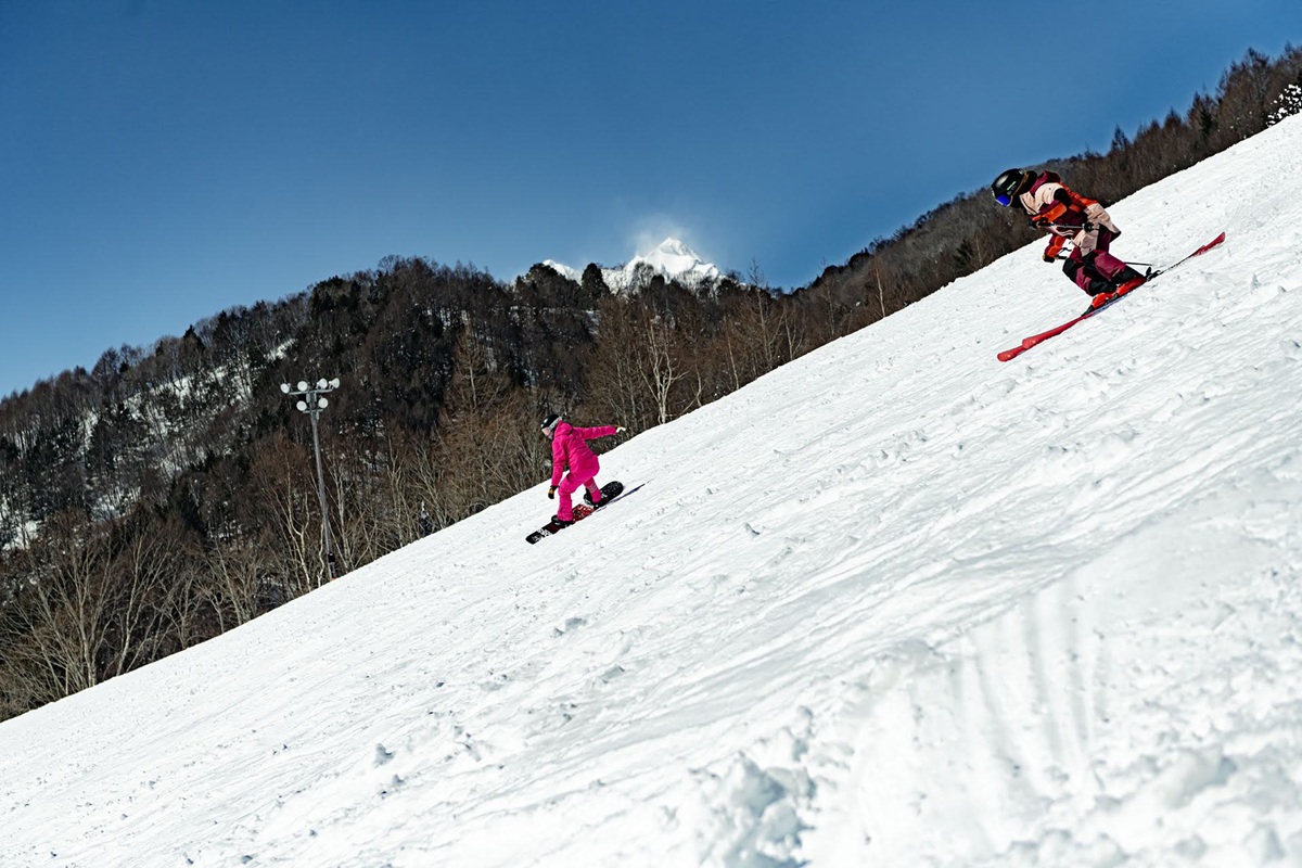 青空の下、Hakuba Valleyの急斜面を滑り降りるスキーヤー
