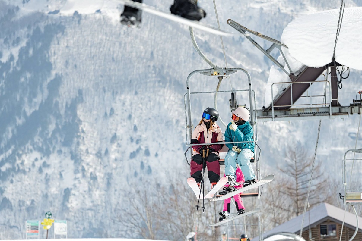 雪山のリフトに乗る2人のスキーヤー
